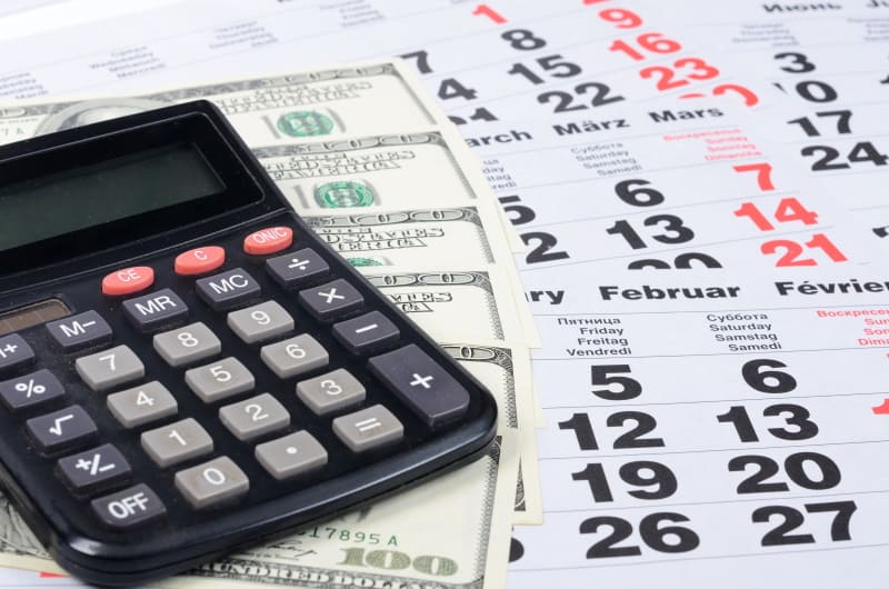 Calendar with stack of $100 bills and a calculator