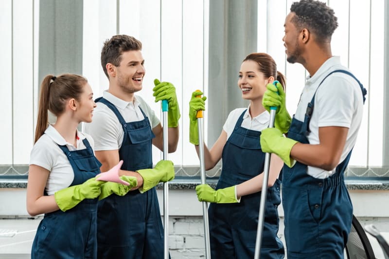Two young men and two young women dressed as professional cleaners standing and talking.
