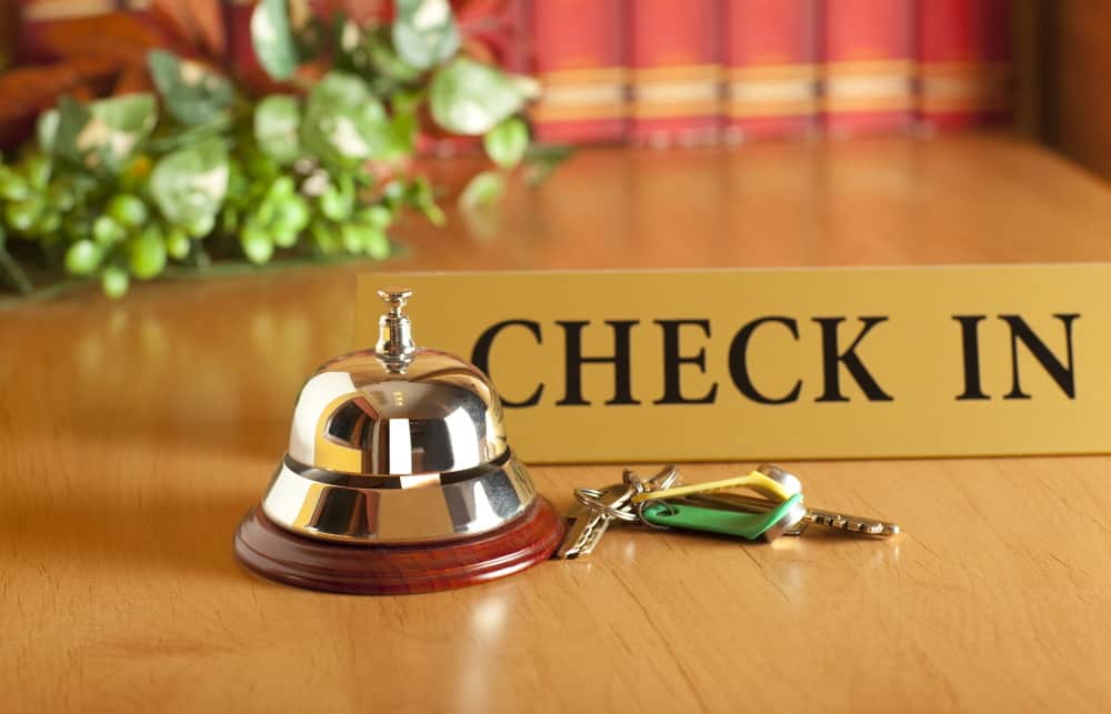 Check in sign on a countertop with a bell and keys.